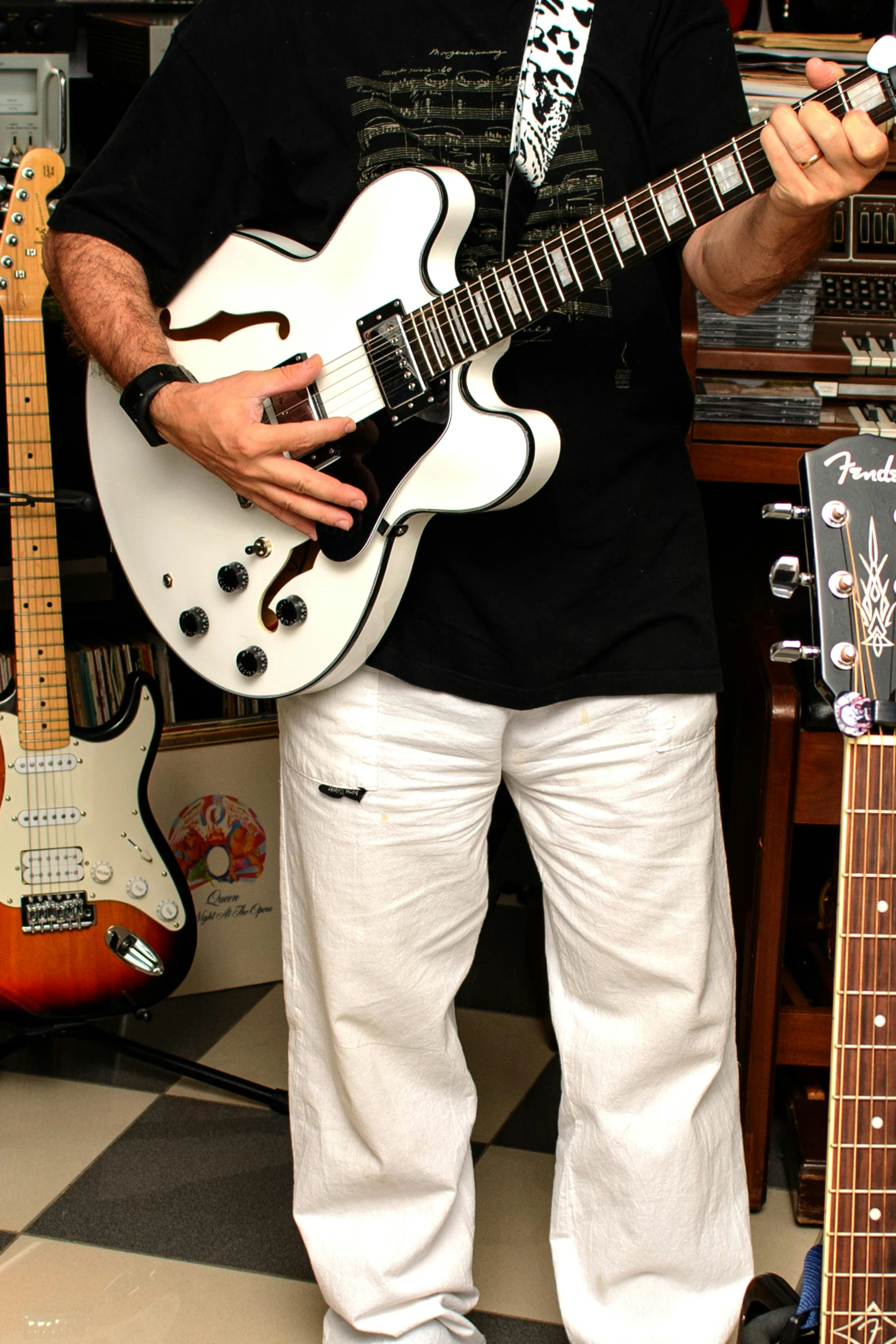a man standing next to a guitar in a room, by Bernie D’Andrea, holding a silver electric guitar, white on black, very detailed curve, official store photo
