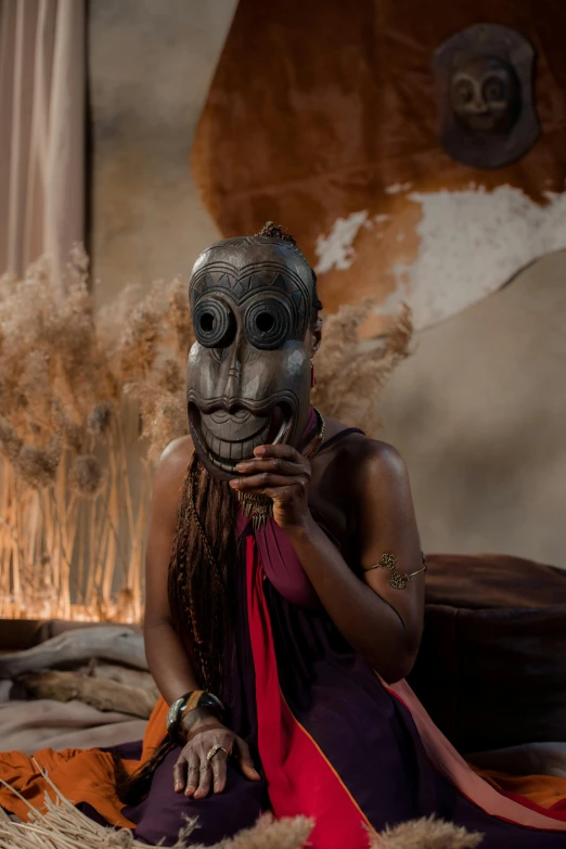 a woman sitting on a bed with a mask on her face, inspired by Afewerk Tekle, afrofuturism, new guinea mud man, production photo, tribal dance, weta workshop