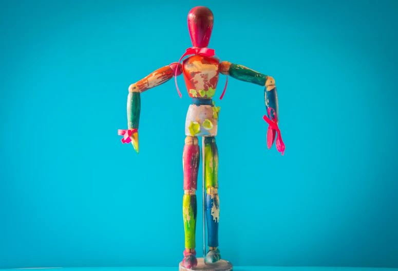 a wooden mannequin holding a pair of scissors, inspired by Jim Dine, unsplash, process art, fuschia and vermillion and cyan, full character body, multi - coloured, 1 figure only