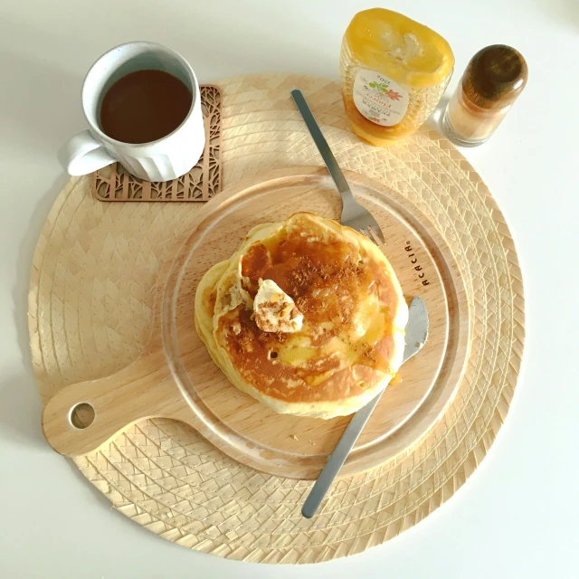 a plate topped with pancakes next to a cup of coffee, hurufiyya, ((oversaturated)), on a wooden tray, 🐿🍸🍋, low quality photo