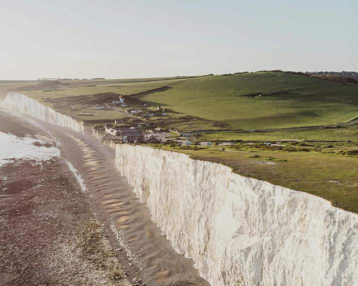 a group of people standing on top of a white cliff, by Charlotte Harding, pexels contest winner, renaissance, rocky ground with a dirt path, sea of milk, over a chalk cliff, white wall complex