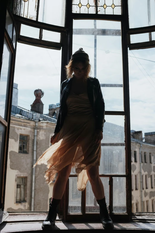 a woman standing in front of a window, inspired by Elsa Bleda, pexels contest winner, dancing elegantly over you, sofya emelenko, wearing jacket and skirt, rooftop party