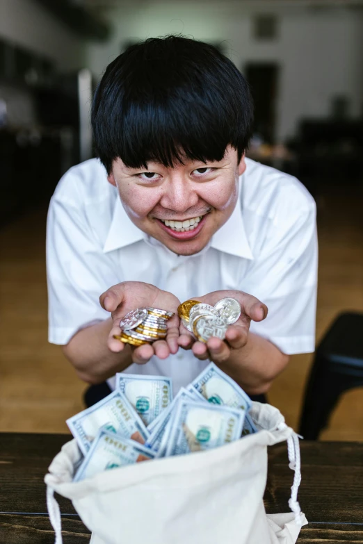 a man sitting at a table with a bag full of money, an album cover, by Jang Seung-eop, pexels contest winner, a boy made out of gold, adafruit, subject is smiling, portrait of a japanese teen