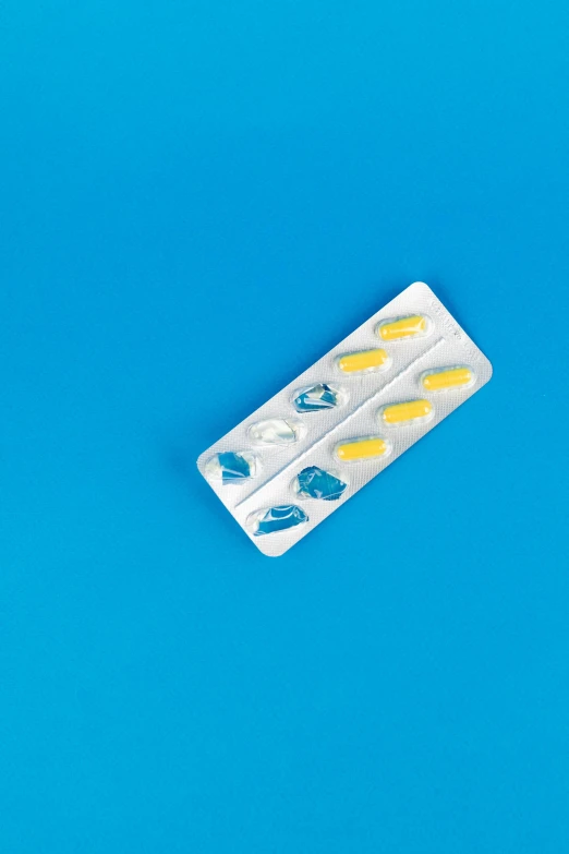 a pill pack sitting on top of a blue surface, a picture, pexels, plasticien, blue and yellow theme, shields, rear facing, high angle