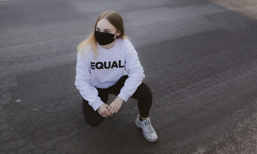 a woman sitting on the ground wearing a face mask, trending on pexels, wearing sweatshirt, lgbt, detailed white, girl standing