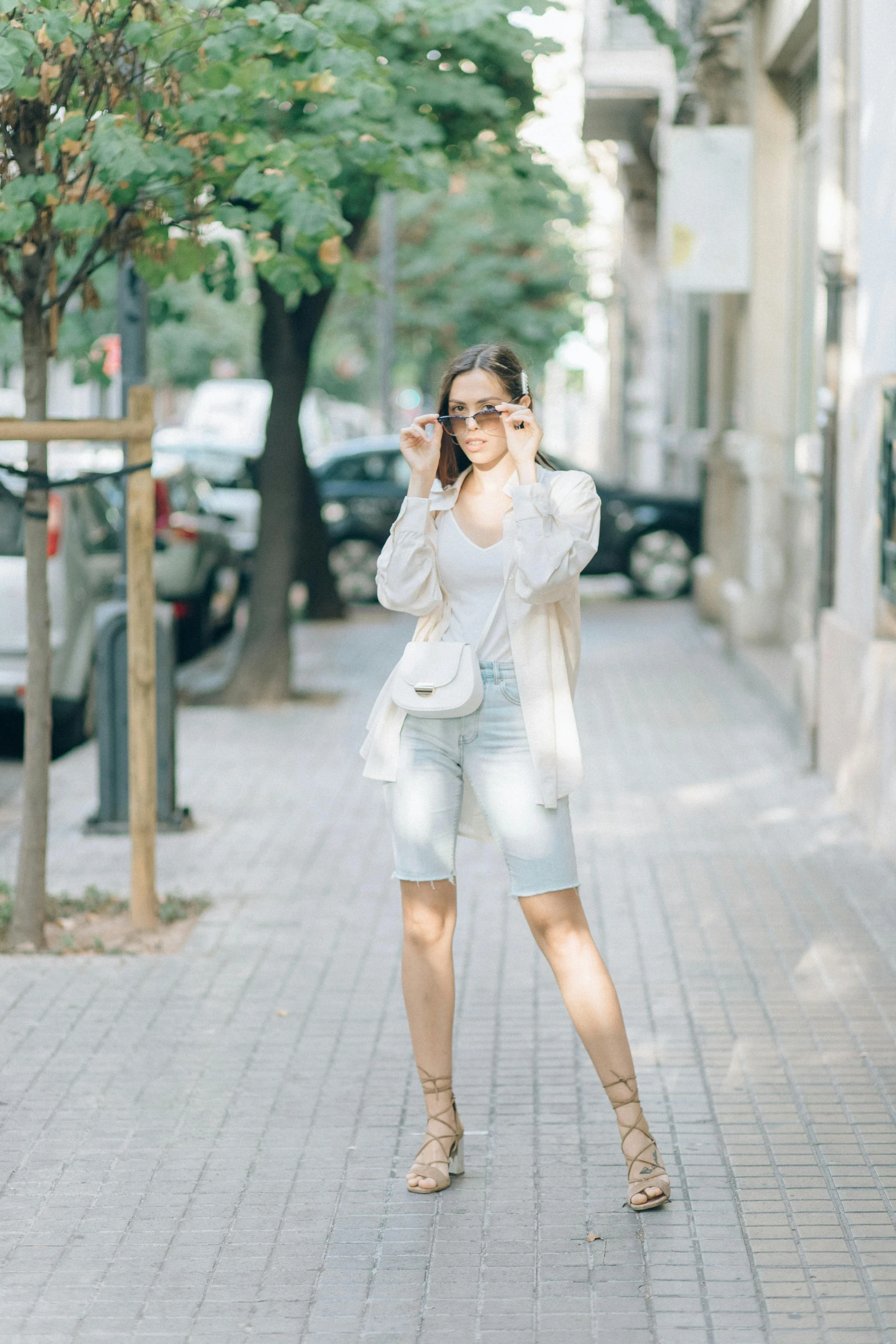 a woman walking down a sidewalk talking on a cell phone, by Hirosada II, pexels contest winner, arabesque, denim short pants, outfit : jeans and white vest, portrait full body, instagram post