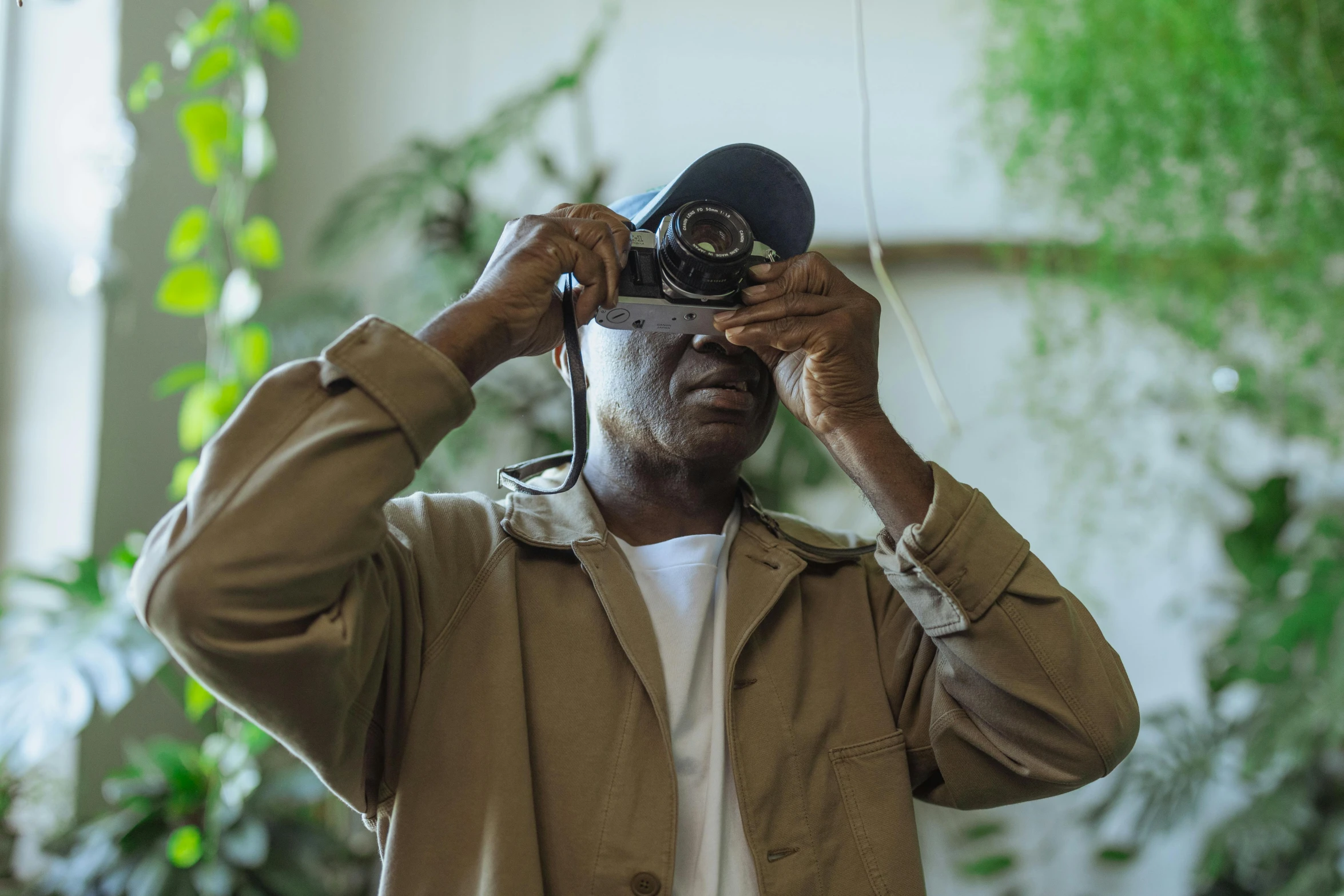 a man taking a picture with a camera, afrofuturism, plant photography, filmstill, wearing vr, blind brown man