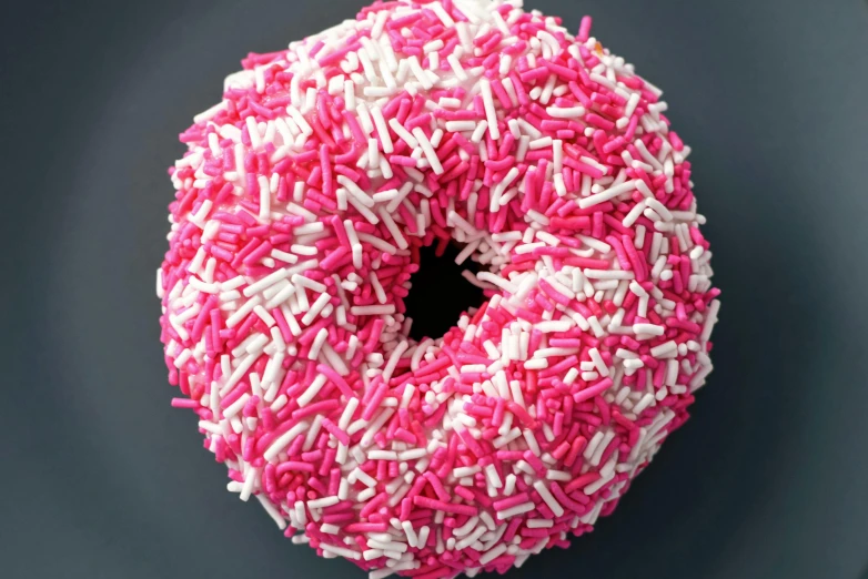 a donut covered in pink and white sprinkles, dark contrast, sculpted out of candy, adafruit, fan favorite