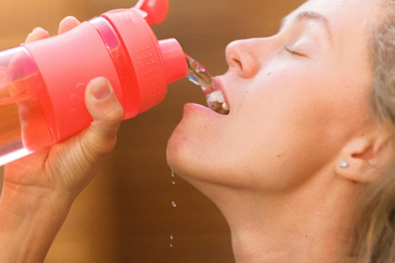 a woman is drinking from a water bottle, by Adam Marczyński, plasticien, pink, up close shot, moringa juice, candy treatments