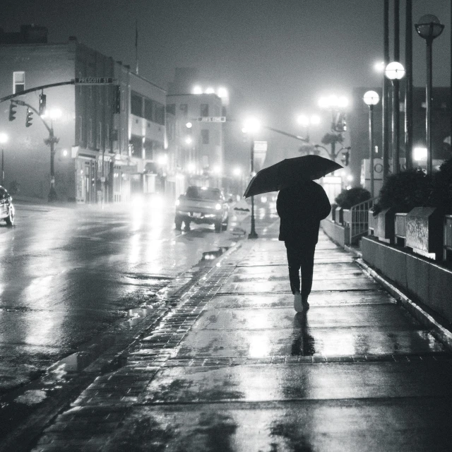 a person walking in the rain with an umbrella, a black and white photo, by Andrew Domachowski, unsplash contest winner, foggy neon night, empty streets, 4k greyscale hd photography, alone!!