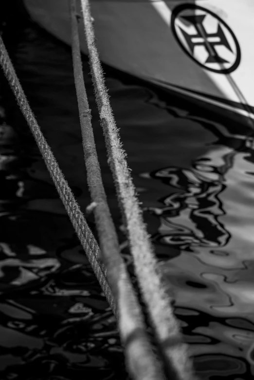 a white boat sitting on top of a body of water, a black and white photo, by Dave Melvin, unsplash, lyrical abstraction, rope bondage, macro details, reflection on the oil, on a yacht at sea