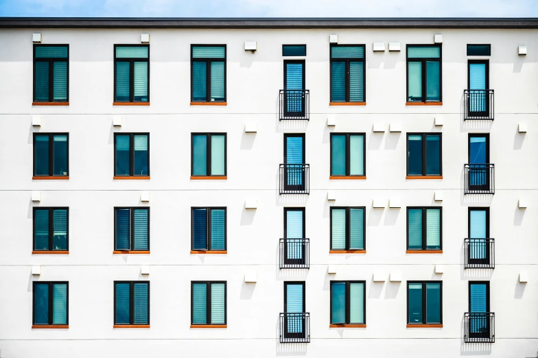 a tall white building with lots of windows, by Carey Morris, unsplash, modernism, neighborhood outside window, contrasting colors, square shapes, black windows