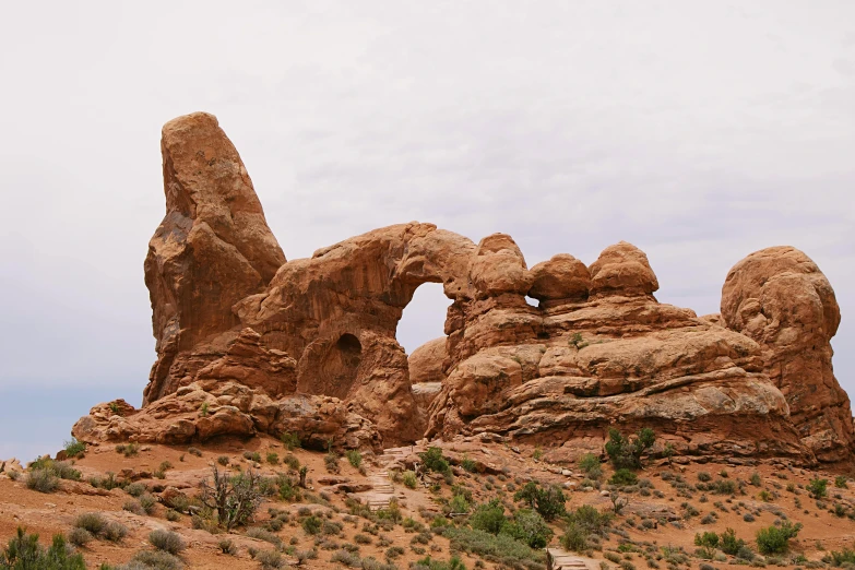 a large rock formation in the middle of a desert, by Pamela Ascherson, unsplash contest winner, art nouveau, tall arches, 2000s photo, slight overcast weather, gnarled