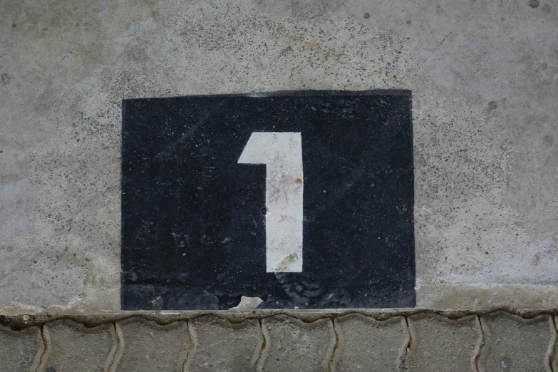 a black and white number one sign on a cement wall, in a square, ( ( dark skin ) ), black, grey