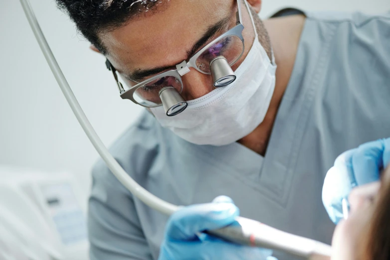 a dentist working on a patient's teeth, by Lee Loughridge, shutterstock, hurufiyya, wearing lab coat and glasses, colour corrected, brown, lower quality