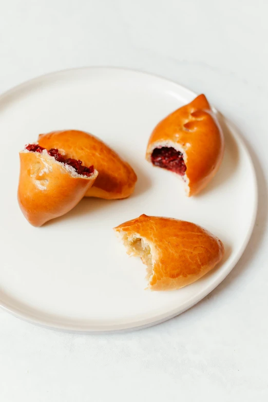 a white plate with three pastries on it, mingei, maroon and white, bao pham, skewed shot, raspberry