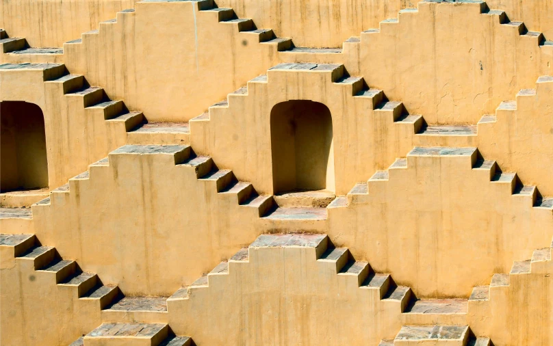 a red fire hydrant sitting on top of a cement wall, an album cover, inspired by Ricardo Bofill, trending on unsplash, op art, stairs and arches, yellow ochre, pyramid surrounded with greenery, india