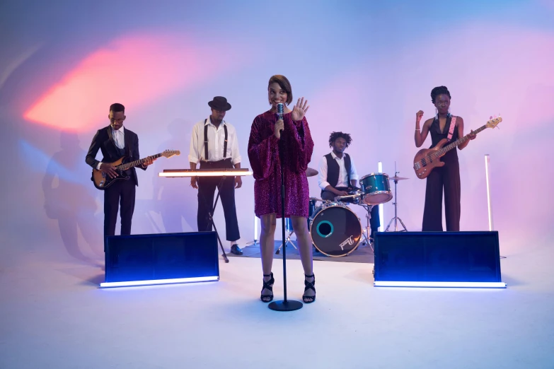 a group of people standing on top of a stage, an album cover, by Winona Nelson, pexels, funk art, performing a music video, maria borges, shot with sony alpha, tv still frame
