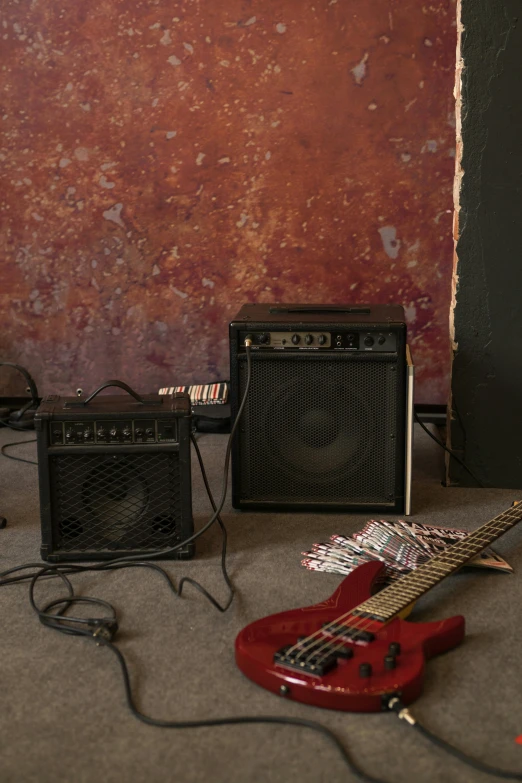 a red guitar sitting on top of a floor next to a amplifier, brown, basement, background image, commercial