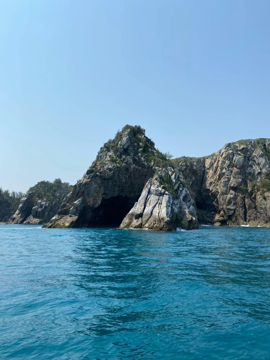 a body of water that has some rocks in it, sōsaku hanga, rock arcs, view from the sea, slide show, secluded