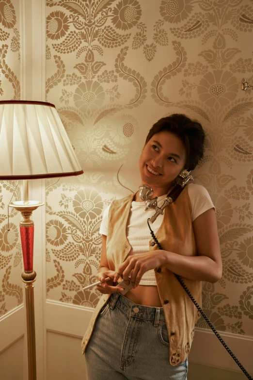 a woman talking on a phone next to a lamp, inspired by Nan Goldin, trending on pexels, art nouveau, kiko mizuhara, cream - colored room, while smiling for a photograph, lasso