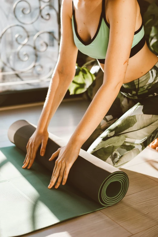 a woman in a sports bra top is rolling up a yoga mat, a picture, trending on pexels, renaissance, thumbnail, a green, black, sup