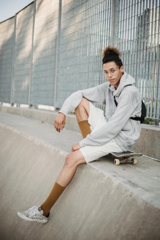 a young man sitting on the edge of a skateboard ramp, trending on pexels, attractive androgynous humanoid, gray shorts and black socks, bella poarch, kevin hou