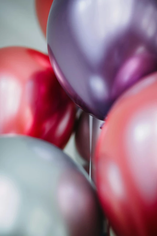 a bunch of balloons sitting on top of a table, by Doug Ohlson, pexels, wine-red and grey trim, purple colour scheme, super close up shot, iridescent titanium