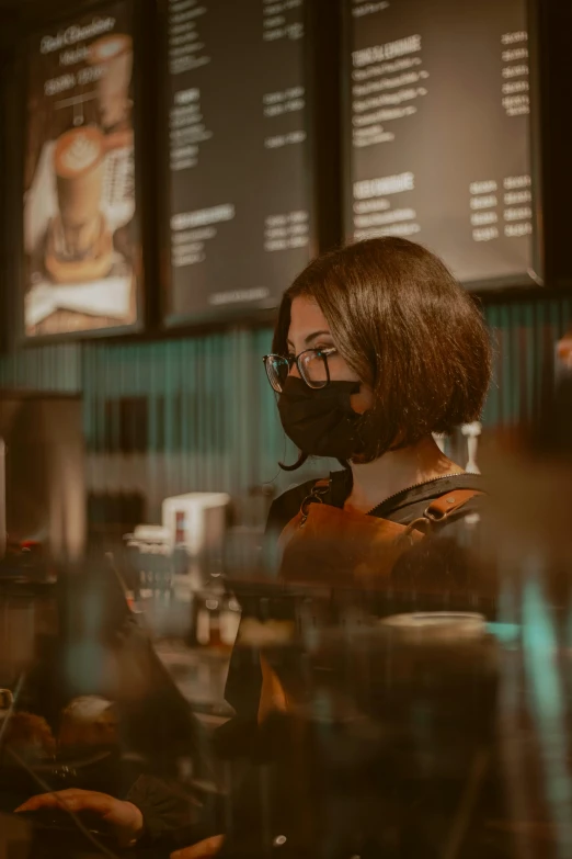 a woman wearing a face mask at a coffee shop, a screenshot, inspired by Elsa Bleda, pexels contest winner, happening, black and brown, cyberpunk photo, aussie baristas, profile pic