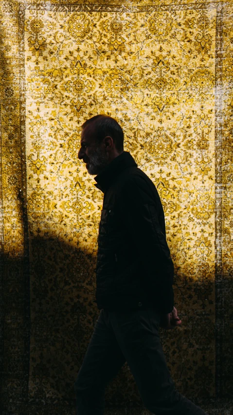 a man walking in front of a yellow wall, an album cover, baroque, demna gvasalia, back light, museum quality photo, iran