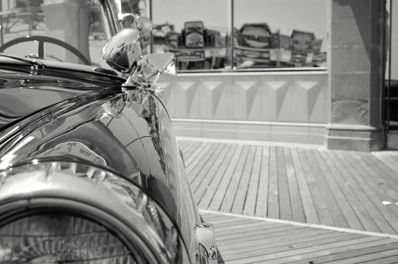 a black and white photo of a classic car, a black and white photo, inspired by Vivian Maier, photorealism, on the deck of a ship, metallic reflections, colour corrected, boardwalk