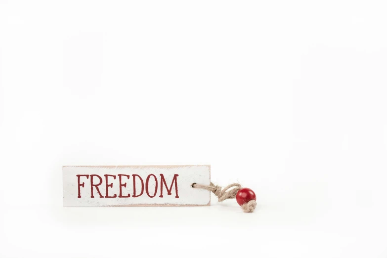 a keychain with the word freedom on it, by Emma Andijewska, white red, wooden decoration, 4k/8, 1944