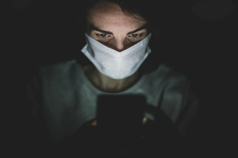 a woman wearing a face mask looking at her phone, by Adam Marczyński, happening, avatar image, mysterious man, nurse, 2263539546]