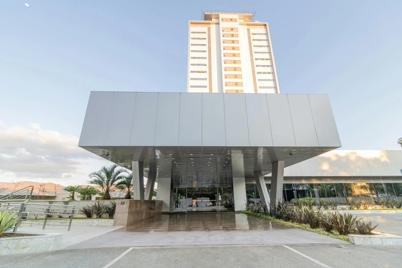 a tall building sitting next to a parking lot, by Felipe Seade, entrance, in a beachfront environment, luiz escanuela, frontal view