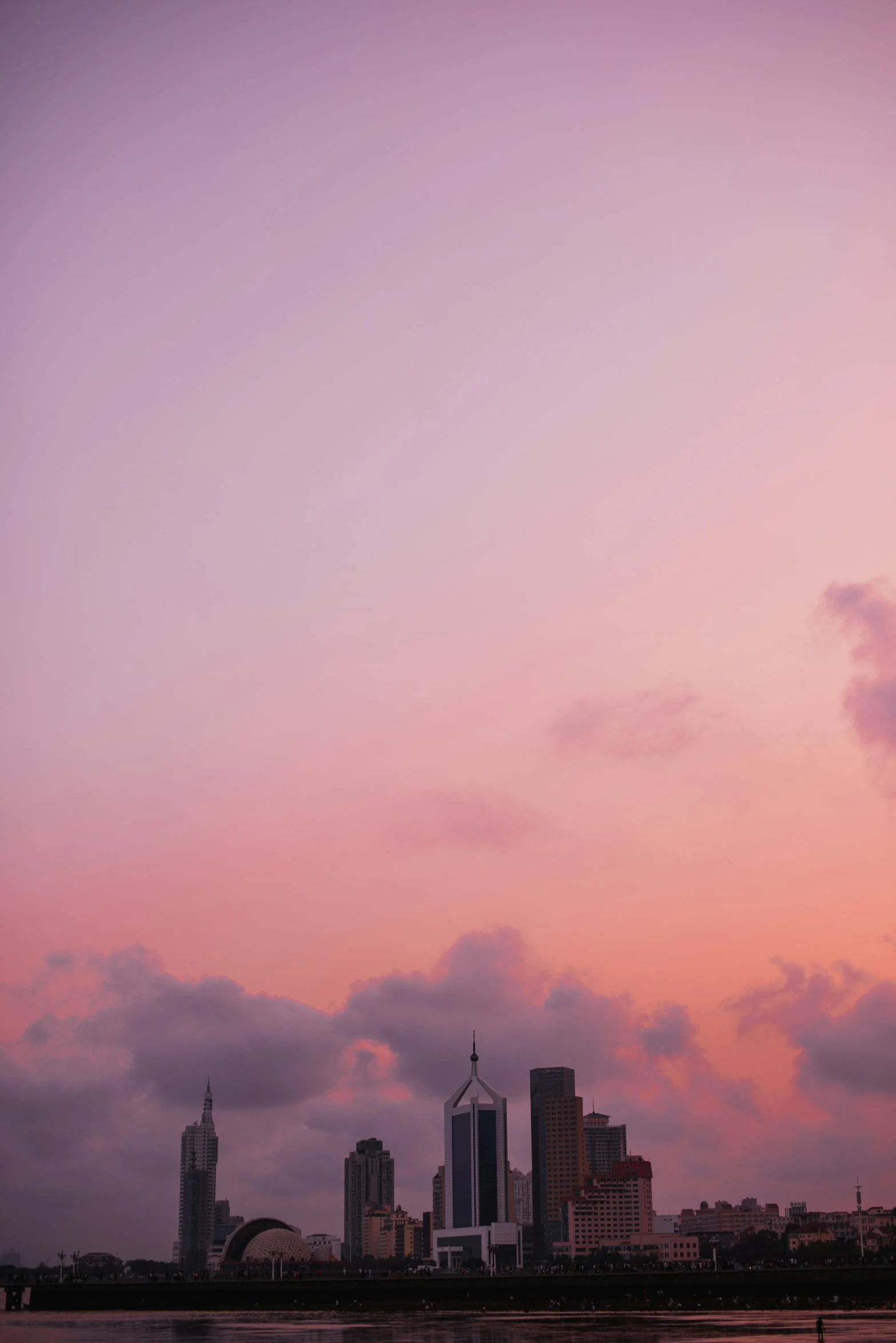 a large body of water with a city in the background, a picture, unsplash, romanticism, orange / pink sky, stacked image, humid evening, purple aethetic