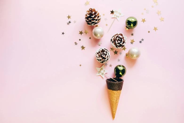 an ice cream cone with christmas decorations on a pink background, by Julia Pishtar, trending on pexels, gold and green, twinkling stars, pinecone, background image