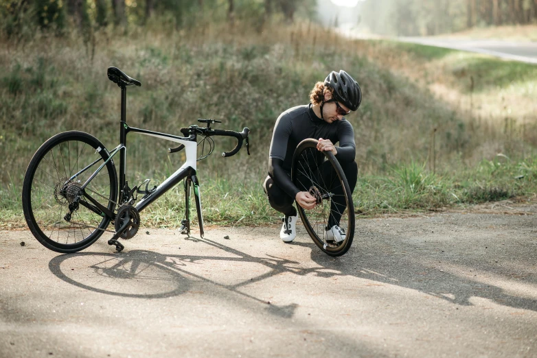 a man kneeling next to a bike on a road, fine fix broken line, nike cycling suit, thumbnail, full product shot