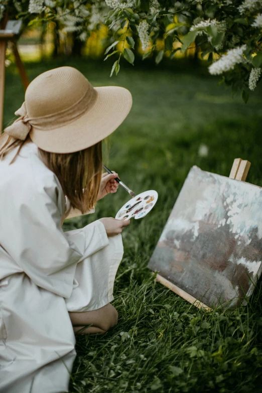 a woman in a hat painting on an easel, pexels contest winner, in garden, white paint, stylish pose, canvas art