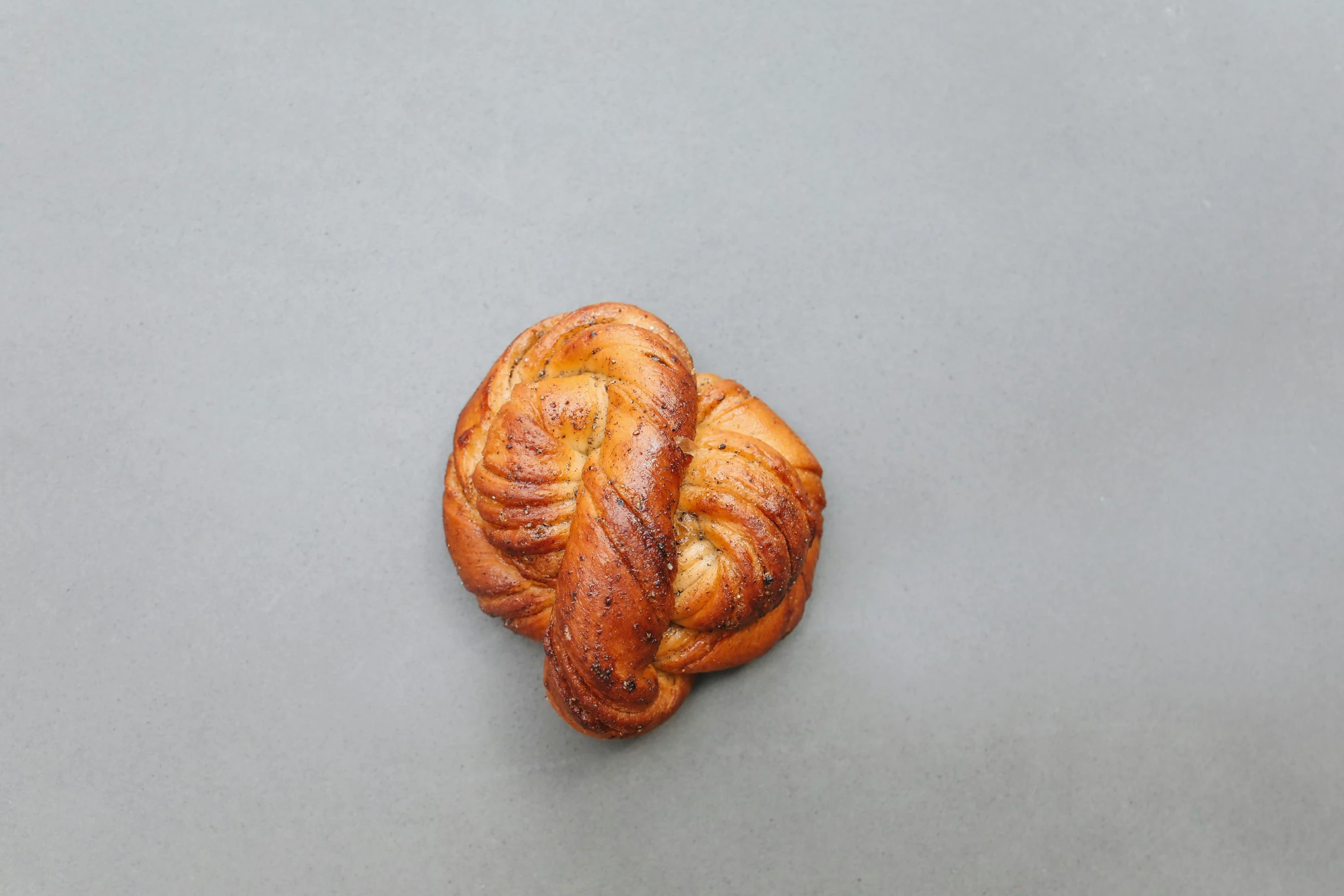 a close up of a pastry on a table, on a gray background, celtic braid, kreuzberg, cinamtic