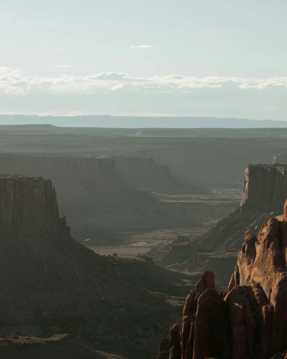 a person standing on the edge of a cliff, a matte painting, unsplash contest winner, moab, low quality photo, valley in the distance, 4 k wild west