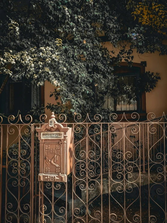 a mailbox in front of a fence with a tree in the background, by Elsa Bleda, pexels contest winner, art nouveau, seville, copper details, balcony, today\'s featured photograph 4k