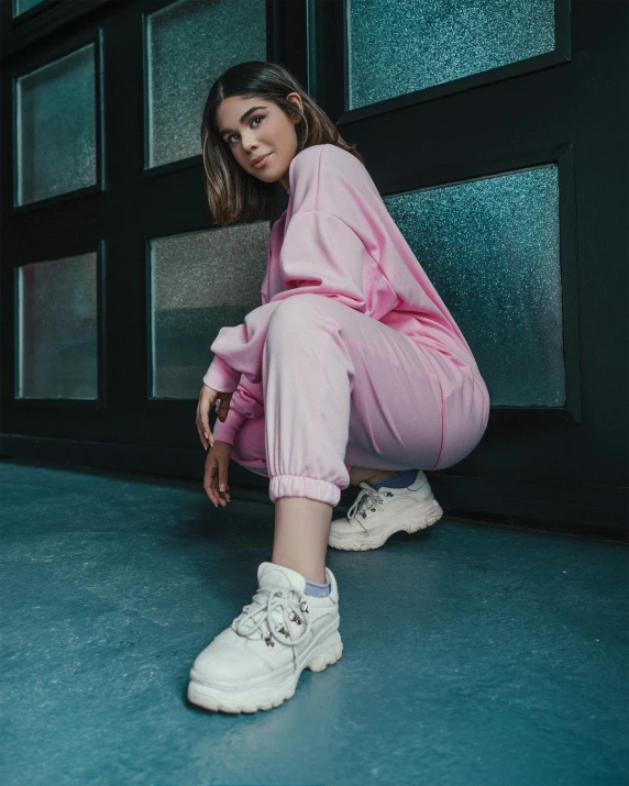 a woman sitting on the ground in a pink outfit, inspired by Elsa Bleda, trending on pexels, graffiti, offwhite, sneaker photo, standing in corner of room, album cover