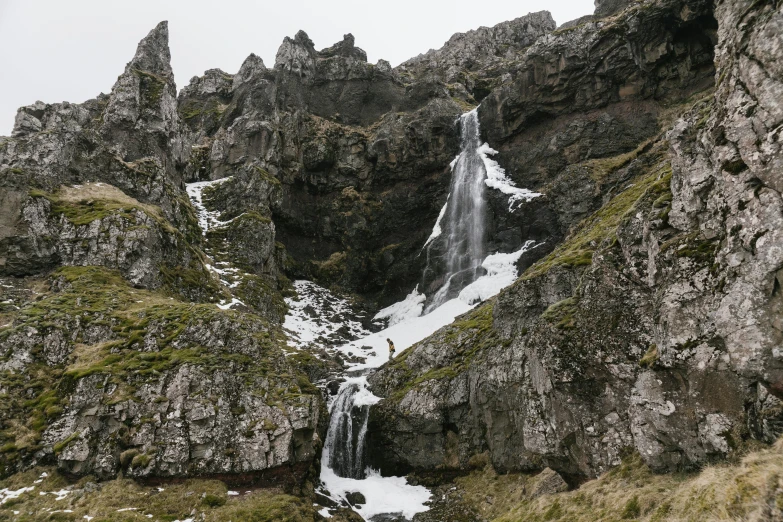 a group of people standing in front of a waterfall, by Hallsteinn Sigurðsson, pexels contest winner, hurufiyya, snowy craggy sharp mountains, thumbnail, high details photo, asymmetrical spires