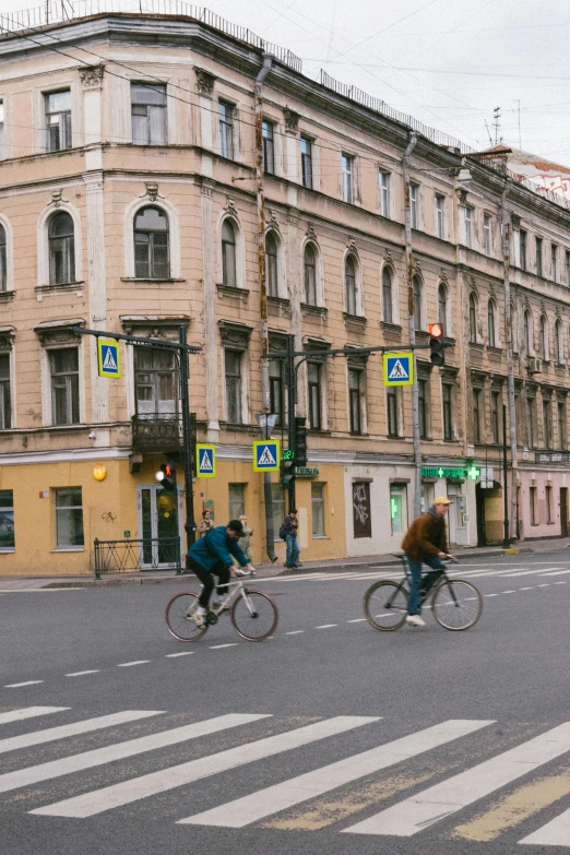 a group of people riding bikes down a street, by Serhii Vasylkivsky, pexels contest winner, socialist realism, tenement buildings, 000 — википедия, square, low quality photo