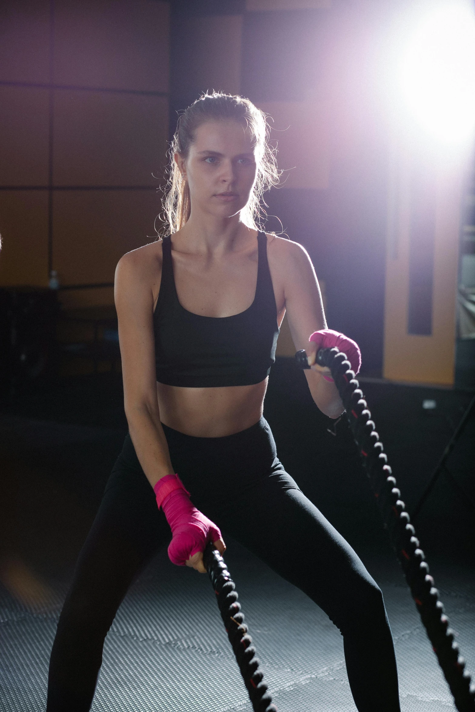 a woman holding two battle ropes in a gym, a portrait, by Robbie Trevino, pexels contest winner, pink, manuka, serious lighting, ad image