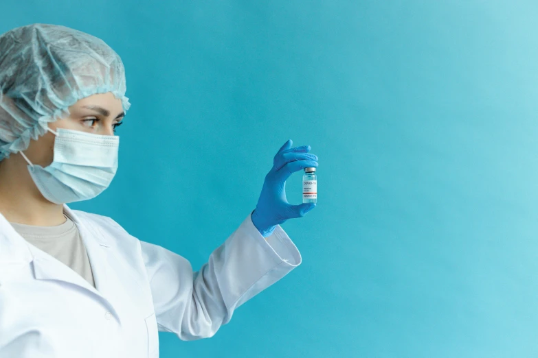 a woman in a lab coat holding a vial, a picture, by Rachel Reckitt, shutterstock, plasticien, with a blue background, nurse costume, masked doctors, bandages