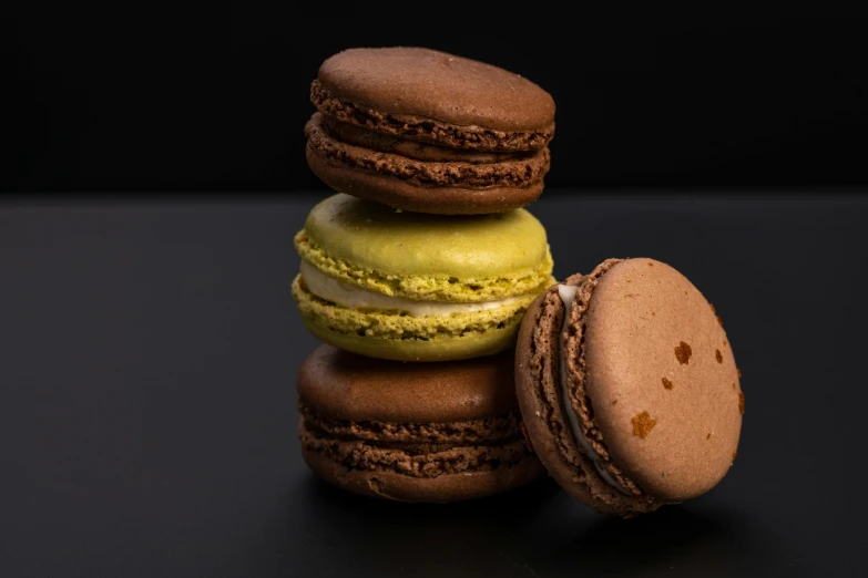 a stack of macarons sitting on top of each other, a portrait, unsplash, dark brown white green colours, ochre, three michelin star, fuji choco