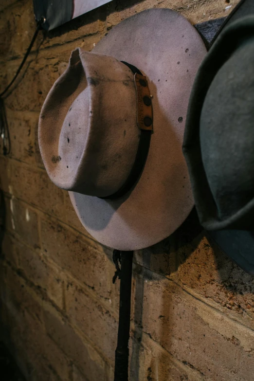 a bunch of hats hanging on a wall, by Lee Loughridge, concrete art, cowboys, detail shot, the back rooms, evening lighting