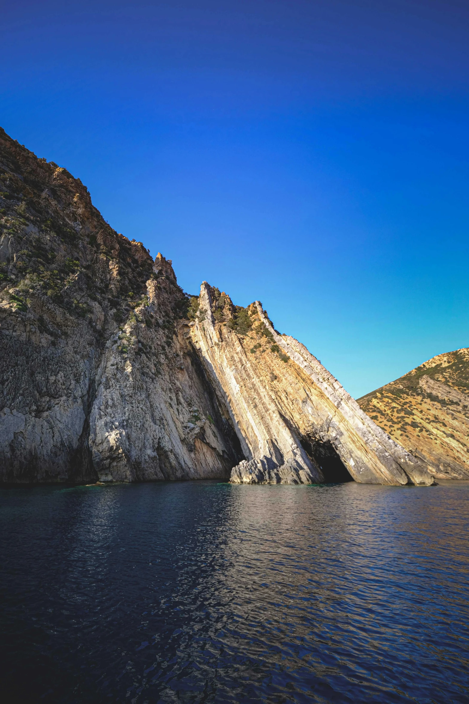 a body of water with a mountain in the background, steep cliffs, rock arcs, mediterranean features, slide show