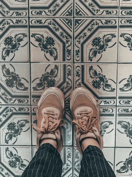 a person standing on top of a tiled floor, a picture, inspired by Anna Boch, trending on unsplash, sneaker photo, !! muted colors!!, 😭 🤧 💔, in the style wes anderson